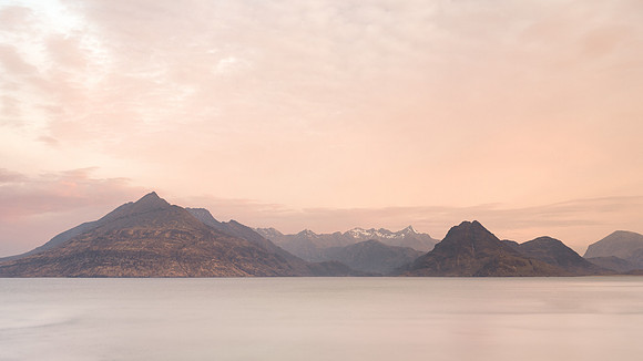 Snow covered mountains across the bay just before sunrise at Elgol, Skye, Scotland.
