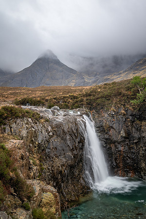 Single waterfall with a backdrop of tall mountains down at the Fairy Pools.