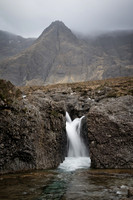 Single waterfall with a backdrop of tall mountains down at the Fairy Pools.