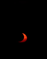 Just the crescent of the sun left as the moon slowly drifts away from the setting sun