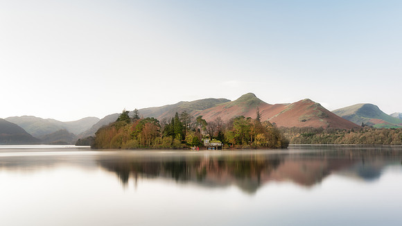 Derwent Isle is reflected in a calm Derwentwater infront of Catbells at sunrise during Autumn.