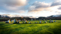 Sunset at Castlerigg Stone Circle with snow covered mountains and long shadows.