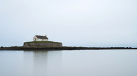 Porth Cwyfan Church reflected on the sea at high tide in Wales.