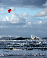 Kite surfer sprays water at the top of a wave during high seas in Cornwall.