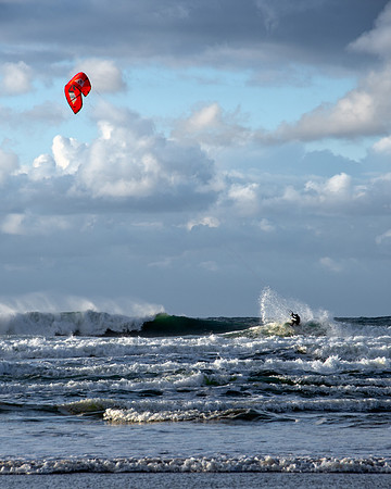 Kite surfer sprays water at the top of a wave during high seas in Cornwall.