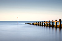 long exposure image of a sea bird sitting on the end of a groyne at sunrise on Dawlish Warren in Devon.