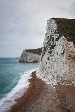 Man standing on Swyre Head Cliff and Bat's head Cliff along the coast from Lulworth Cove and Durdle Door.