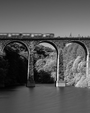 Black and white image of a train to Blackburn crossing Entwistle Viaduct over Wayoh Reservoir.