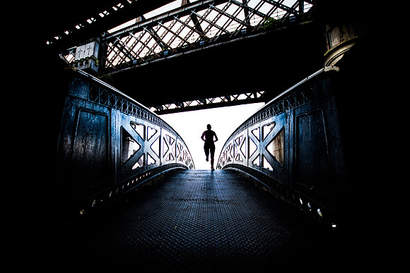 Silhouette of a runner crossing the Victorian footbridge at Castlefield in Manchester
