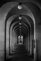 A man walking past a long corridor of arches next to the town hall in Manchester.