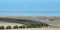 A group of people doing yoga on the beach next to the sea defences replicate the wind turbines with their arms at New Brighton near Liverpool.
