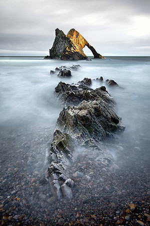 Bow Fiddle Rock at Portknockie in the sun with prehistoric rocks that look like a fossil of a dinosaur