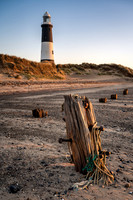 Spurn point Lighthouse and worn out jetty posts at sunrise.