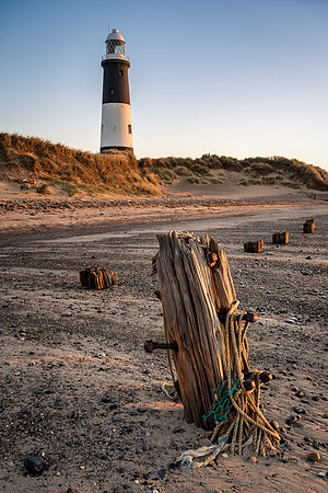 Spurn point Lighthouse and worn out jetty posts at sunrise.