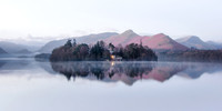 Derwent Isle is reflected in a calm misty Derwentwater infront of Catbells before sunrise during late winter.