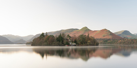 Derwent Isle is reflected in a calm Derwentwater infront of Catbells at sunrise during Autumn.