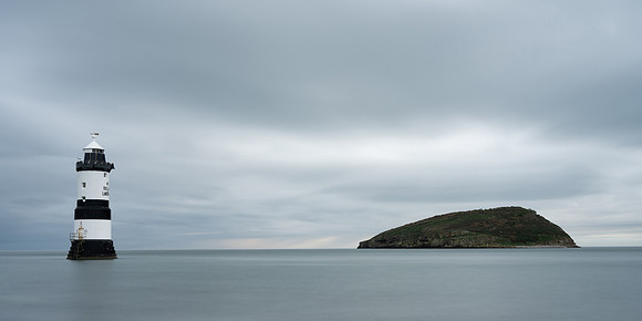 Long Exposure image of Penmon lighthouse and Puffin Island on an overcast day at sea.