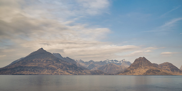 Snow capped mountains across the sea as the sun rises over Elgol on the Isle of Skye.