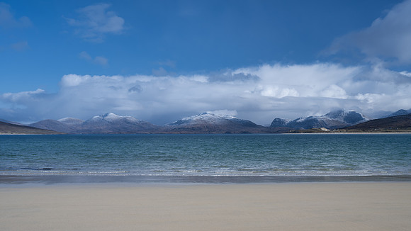 Hebridean snow capped mountains across the bay at Horgabost on the Isle of Harris, Scotland.