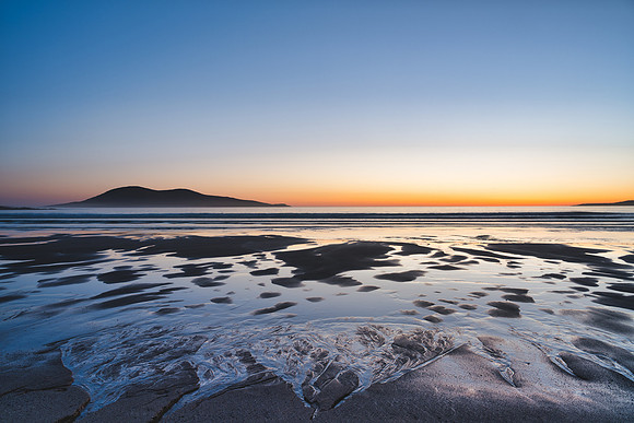Reflections in the sand on a Ceapabhal Sunset on Nisabost beach on Isle of Harris, Scotland.