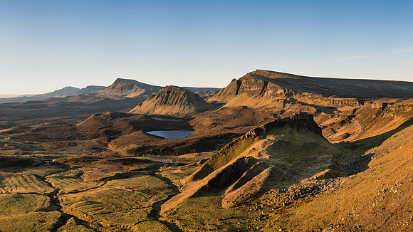 The sunrise turns all the mountains, lochens and rock slides golden at the Quiraing on Isle of Skye.