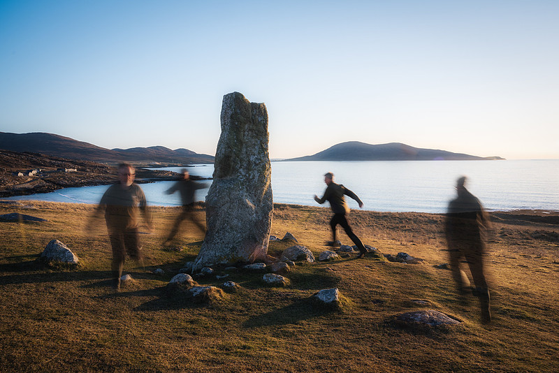 Man runs round a standing stone on Isle of Harris, Scotland.