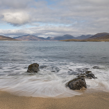 Waves crashing on Bagh Steinigidh with the North Harris mountains across the bay.