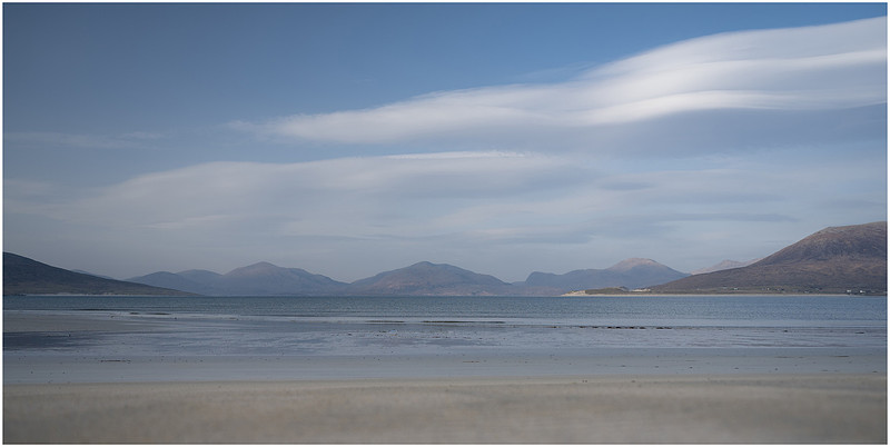 Mountains in the distance and white sands and waves on the beach overlooking Luskentyre on the Isle of Harris
