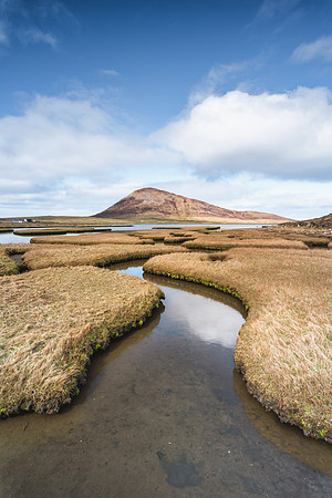 Small winding river at Northton Salt Flats on Lewis and Harris with Ceapabhal catching the sun in the background.
